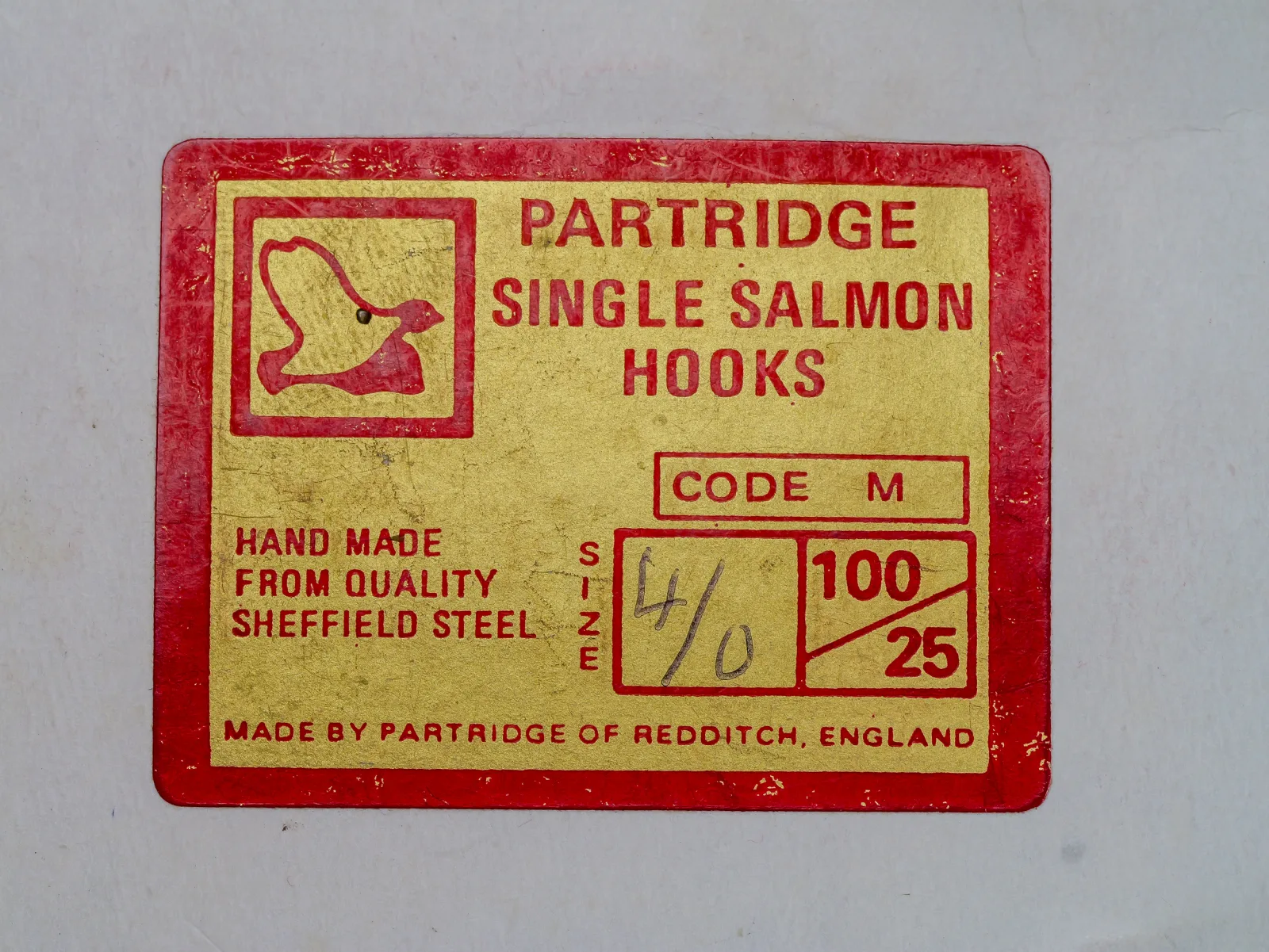 Red-bordered gold Partridge Single Salmon Hooks box label, Code M, with size 4/0 written by hand