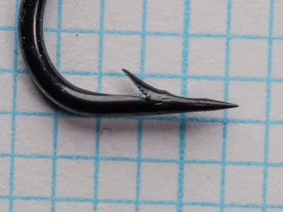 Black blued salmon hook displayed at angle showing barb and bend detail