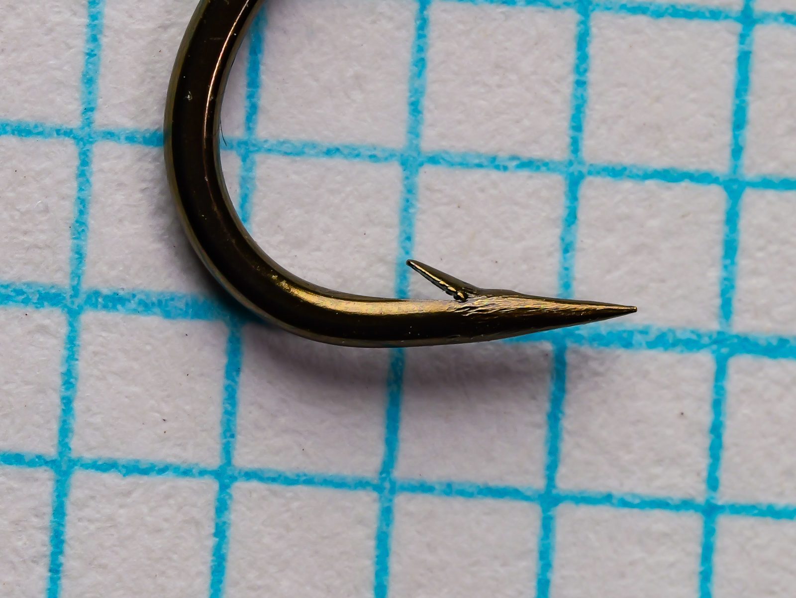 Partridge D3ST Size 6 hook point and barb detail — extreme close-up — needle-point taper, perpendicular barb placement, mechanical filing marks, superior point geometry