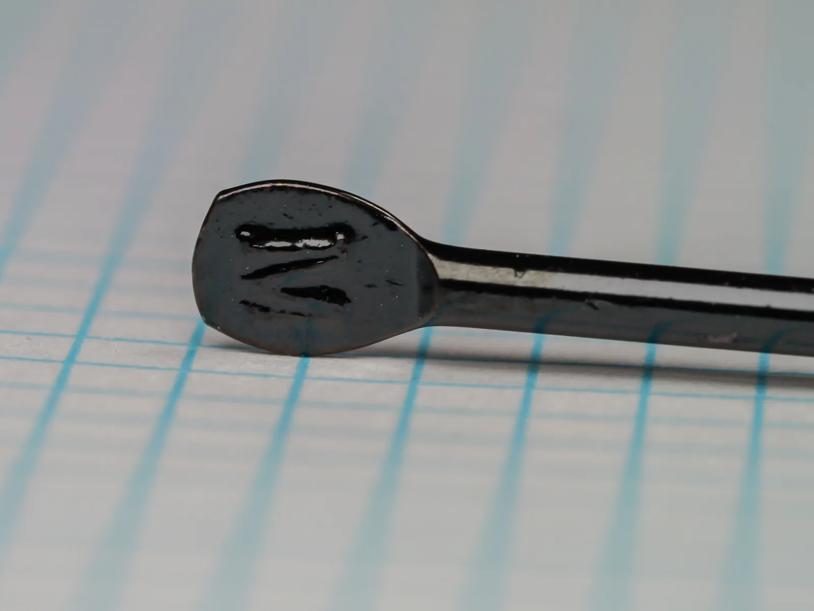 Mustad 3455 Kinsey Size No. 5 — flatted eye detail showing japanned finish and spade-like blind shank terminus — on 1/10 inch measurement grid