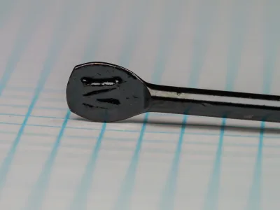 Mustad 3455 Kinsey Size No. 5 — flatted eye detail showing japanned finish and spade-like blind shank terminus — on 1/10 inch measurement grid