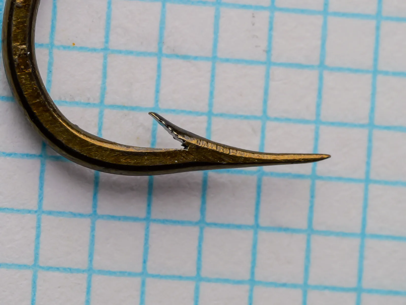 Mustad 3822 O'Shaughnessy Hook — close-up of point and barb showing hollow point geometry and bronzed finish — size 1/0 — measured on grid