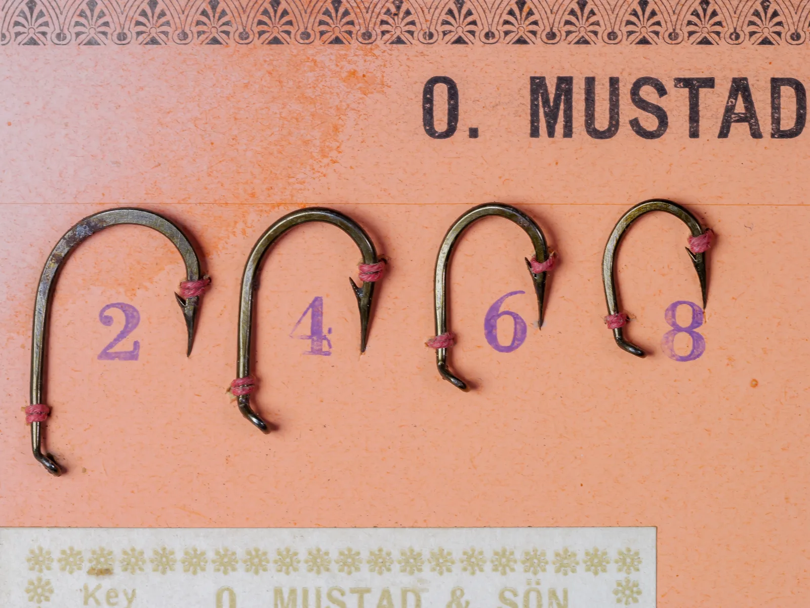 Mustad 7958 F Viking Hooks — four sizes (2, 4, 6, 8) displayed on original vintage packaging, showing turned-down tapered eye, wide round bend, and forged reversed point, bronzed finish