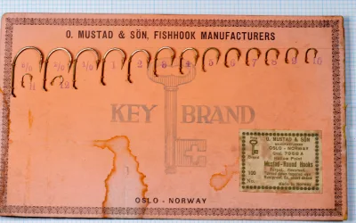 Mustad 7958 A salesman sample card full view — terra-cotta paper stock with Key Brand logo, size range display, Oslo-Norway manufacture marking