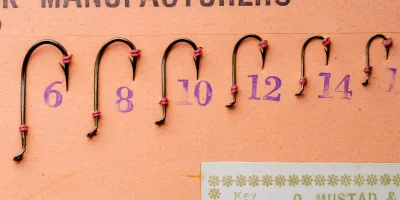 Mustad 7974 Viking Hooks — display card showing six hook sizes (6, 8, 10, 12, 14, 16) threaded on pink silk in three rows — bronzed finish — size range visible on measurement grid