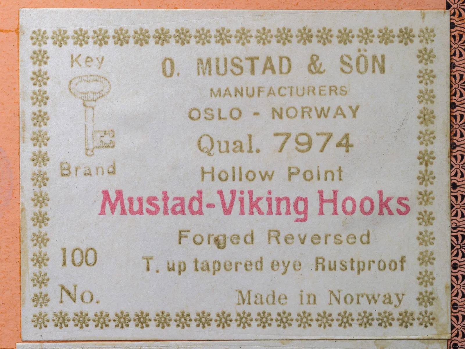 Cream Mustad Key Brand label for quality 7974, printed with Hollow Point, Mustad-Viking Hooks, Forged Reversed, turned-up tapered eye, Rustproof, and Made in Norway.
