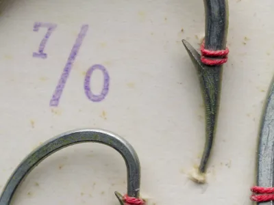 Mustad 92628 ST — detail of hook point showing reversed offset and hollow point geometry — specimen mounted with red wrapping thread — tinned finish