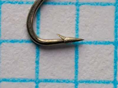 Partridge K14ST Size 16 — side profile showing the superior point, limerick bend geometry, and bright-steel finish — hook measured on grid