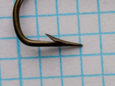 Pflueger Sneck No. 4 — side view showing bend profile and point geometry — size 4 — bronzed finish with light patina