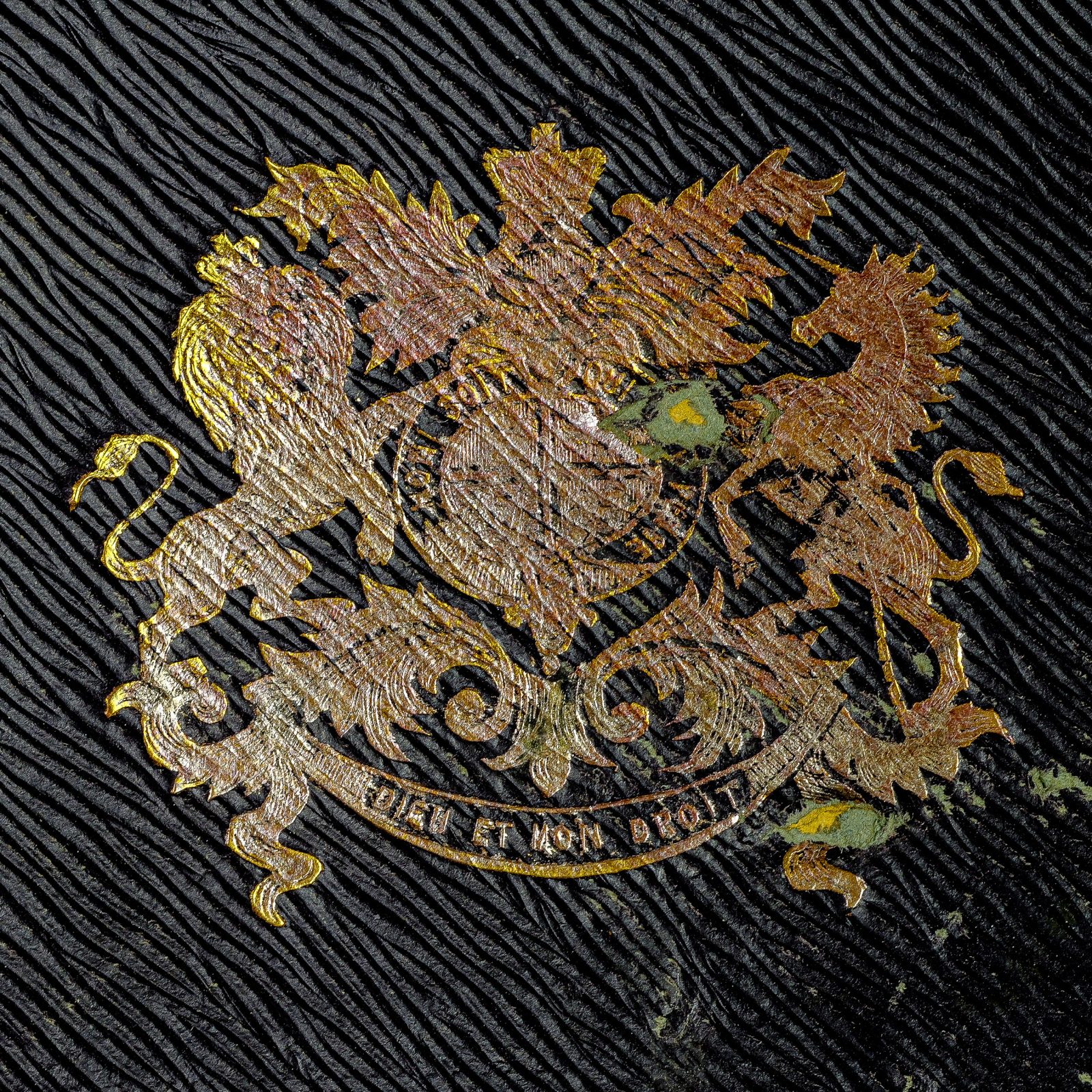Heraldic coat of arms on Bartleet card cover — close-up of multi-color hand-engraved emblem with lion, dragon, and shield device