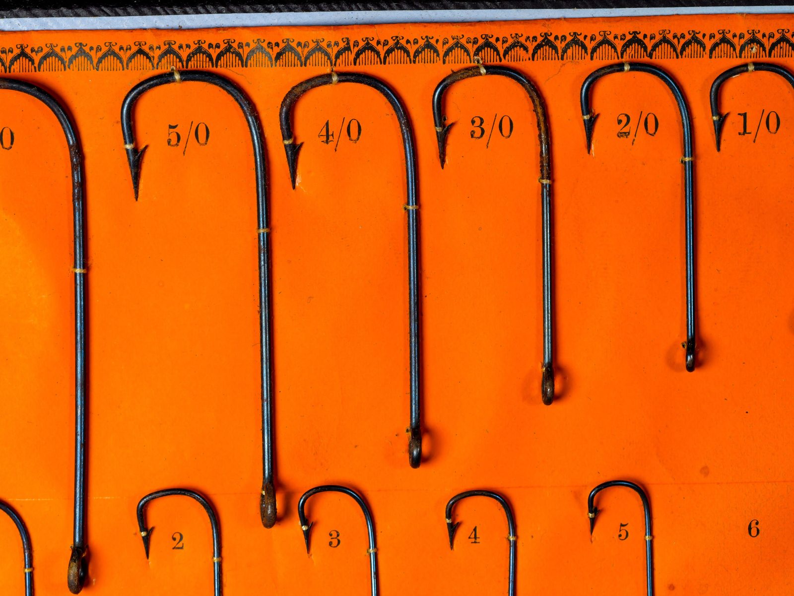 Kendal Sneck hooks sizes 5/0 through 1/0 — upper row detail showing larger fly-hook sizes and blued finish under even lighting