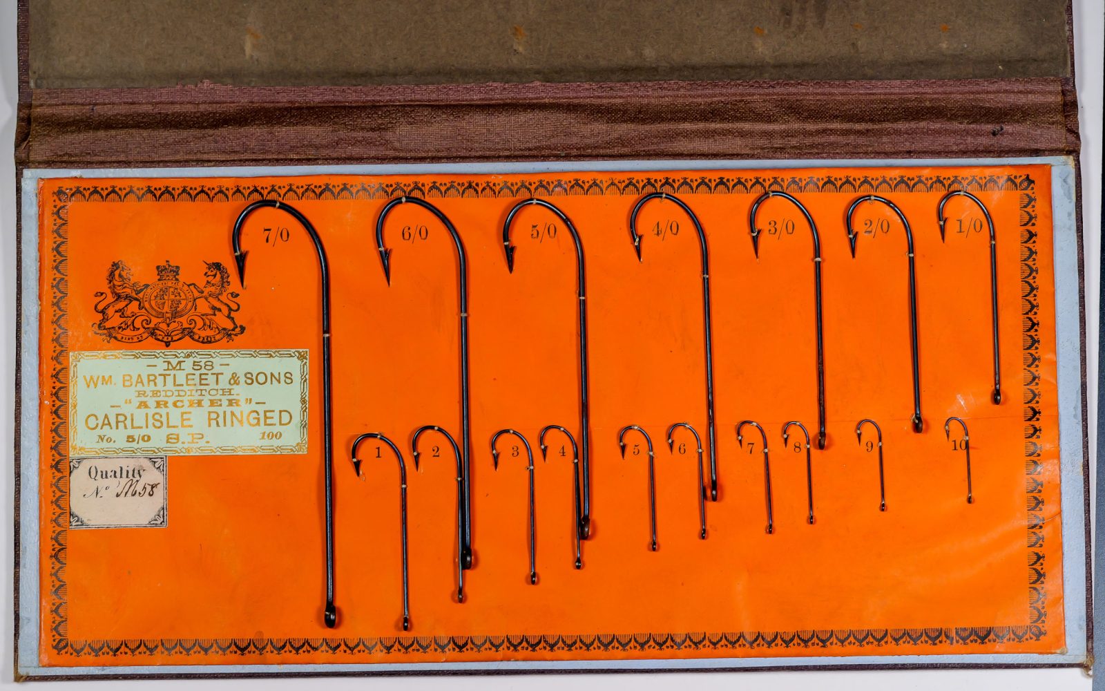 Wm. Bartleet M58 Archer Carlisle Ringed sales card display — full card showing mounted hook examples in sizes 1/0 through 7/0 on orange card stock with decorative letterpress border and label