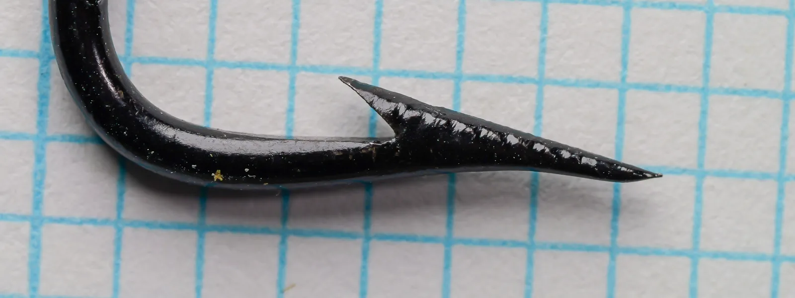 John James & Sons Best Steel Limerick Salmon Hook size 8/0 — close-up of hook point and barb showing superior point taper and japanned finish on measurement grid