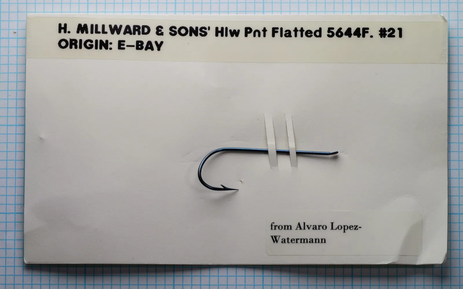 H. Milward & Sons 5644F size 21 hollow point salmon hook mounted on collector documentation card — flatted eye construction and overall proportions visible on measurement grid