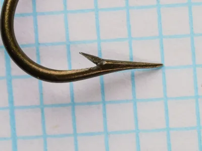 Mustad 3319 A — close-up of hook point from below, showing superior point profile and barb geometry, size 20