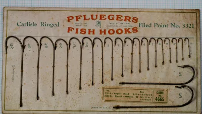Pflueger Carlisle 3321 — display card showing full range of hook sizes from 6/0 to 16 with examples mounted — product heritage and company branding — early 20th century