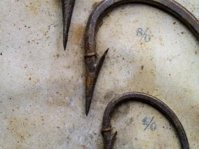 Pflueger O'Shaughnessy size 8/0 — extreme close-up of point tip showing concave taper and barb positioning, filed point inner face detail