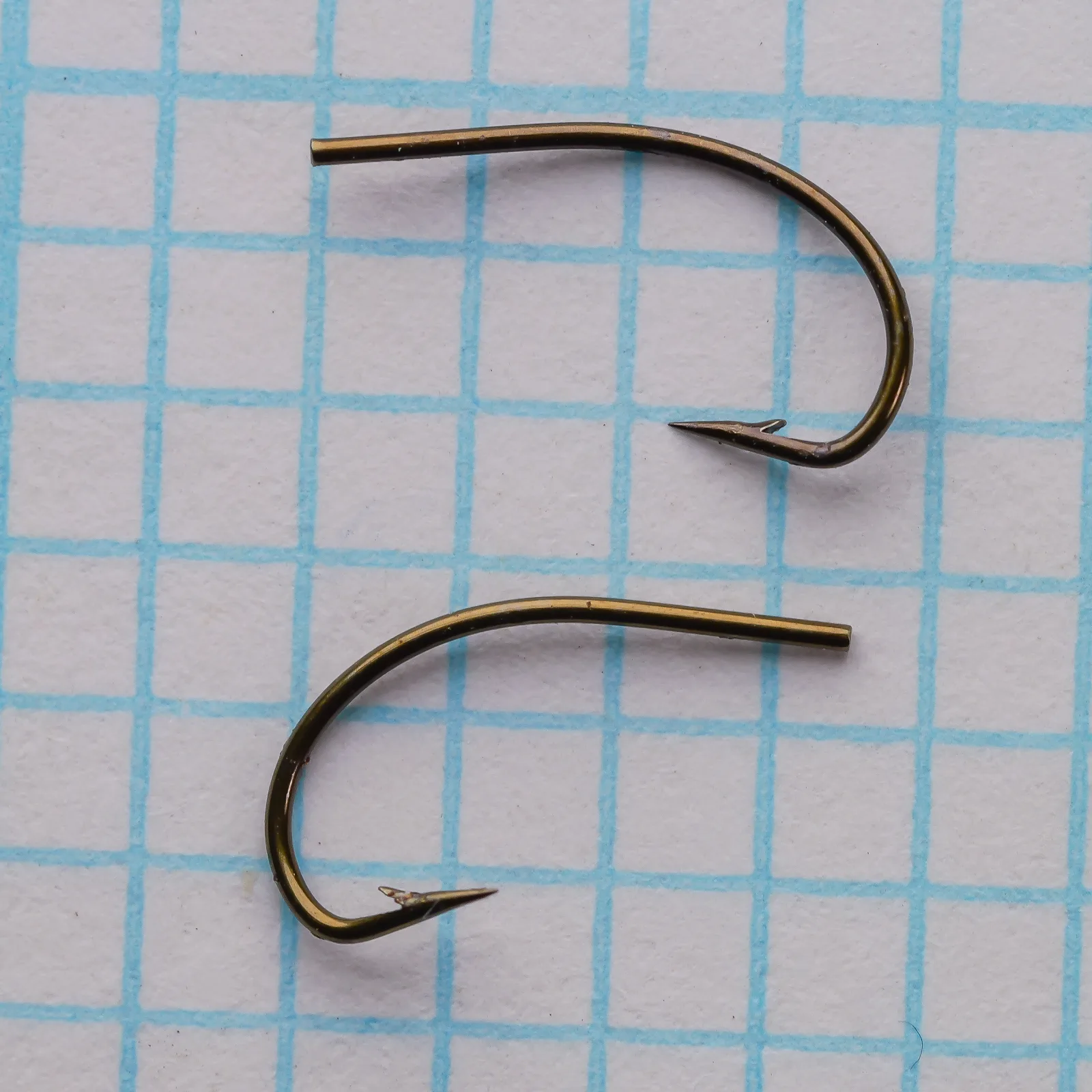 Partridge K4A Grub Hook size 14 — two specimens shown side-by-side on measurement grid — curved shank and tapered blind eye visible — bronzed finish
