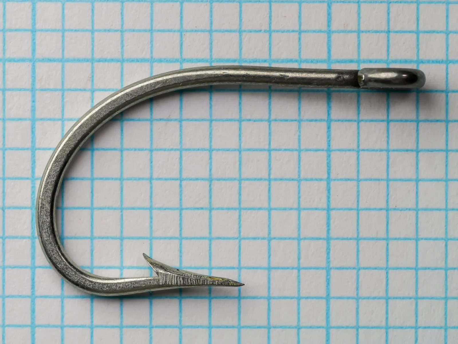 Pflueger 25521-T O'Shaughnessy Hook — side profile showing bend and ring eye — size 4/0 — tinned finish on measurement grid