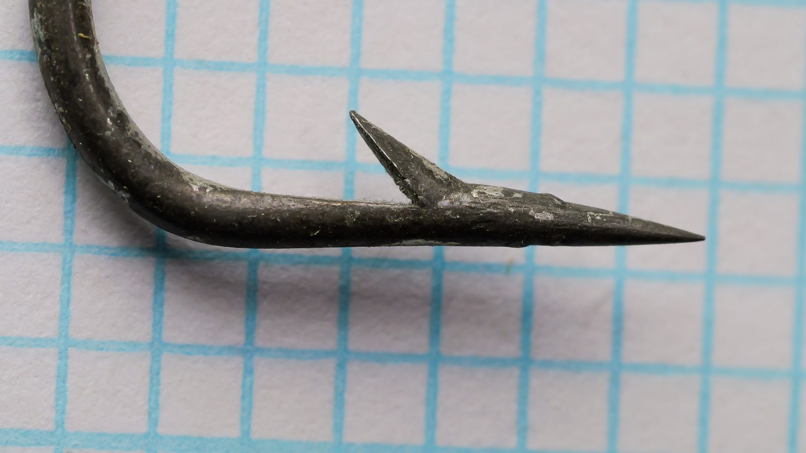 Pflueger 5212-T hook point — close-up showing needle-point spear geometry and barb placement at 6/0 size — measurement grid