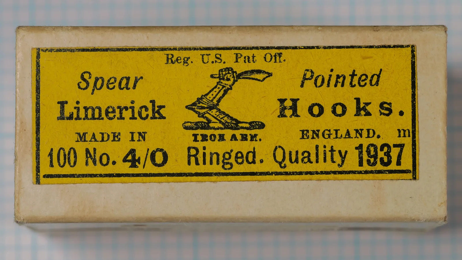 Size 4/0 Iron Arm hook box with a yellow label printed in black, an armored arm device at center, and a clean card surface.