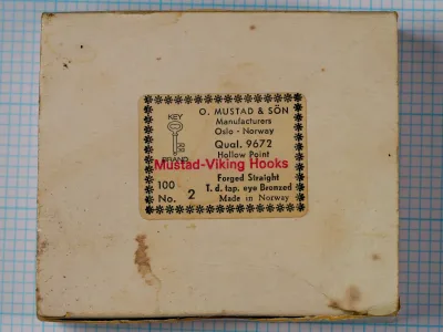 Mustad 9672 Size 2 — cardboard box label — aged vintage packaging — showing tan/cream label with decorative border and red 'Mustad-Viking Hooks' text