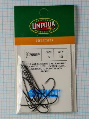 Tiemco TMC 765SP Streamer — clamshell package front showing Size 6 qty 10 specification label with black nickel hooks visible inside opened packaging on measurement grid