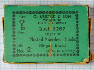 Mustad 3262 Aberdeen size 5/0 blued hook point detail showing sharp barbed tip on measurement grid