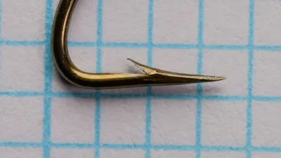 Mustad 36680 Streamer Size 6 — hook profile showing turned-down tapered eye and complete bend profile, hollow point geometry visible, bronzed finish on measurement grid