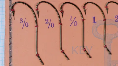 Mustad 3840 Centripetal Hooks — full sales card showing nine sizes in progression from 3/0 to 6 — bronzed finish hooks on original orange card with gold letterpress text