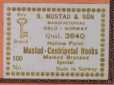 Mustad 3840 label — text detail reading 'O. MUSTAD & SON MANUFACTURERS OSLO - NORWAY Qual. 3840 Hollow Point Mustad-Centripetal Hooks Marked Bronzed Special Made in Norway' — gold letterpress on cream background