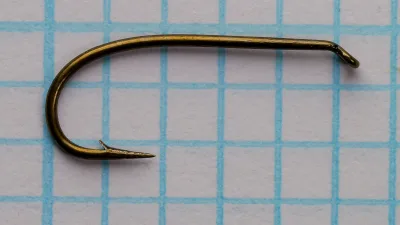 Size 1 Allcock Best Hollow Point hook — photographed on measurement grid — side profile showing Sproat bend, hollow point, and bronzed finish