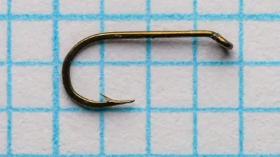 Ray Bergman Red Label hook — side profile showing round bend and tapered turned-down eye — size 16 equivalent — bronzed finish on grid