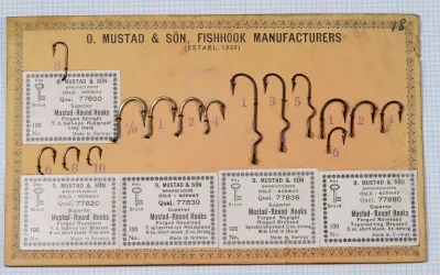 Mustad Superior Mustal-Round Hooks sales card showing five quality variants (77800, 77820, 77830, 77836, 77880) with mounted specimens and original packaging labels on tan cardstock with decorative border