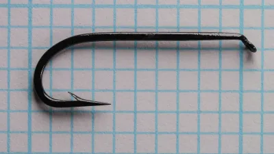 Mustad 9100 size 6 hook profile — side view showing tapered eye, Limerick bend, 3X long shank, and black japanned finish on 1/10-inch measurement grid
