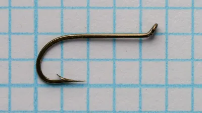 Mustad 94842 Viking size 14 — left profile showing turned-up tapered eye, straight shank, and bend geometry — bronzed finish on 0.1-inch grid