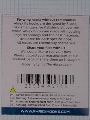 Back of a flat paper packet with two text blocks, a barcode, a yellow warning triangle and a dark blue band at the bottom.