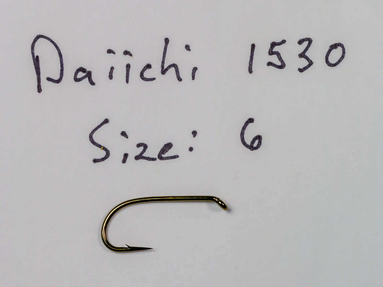 Handwritten note reading Daiichi 1530 and Size: 6 above a bronze fly hook on a plain light sheet.