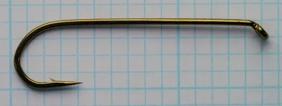 Side view of a bronze-colored size 4 streamer hook on graph paper, eye at right turned down, point at lower left.