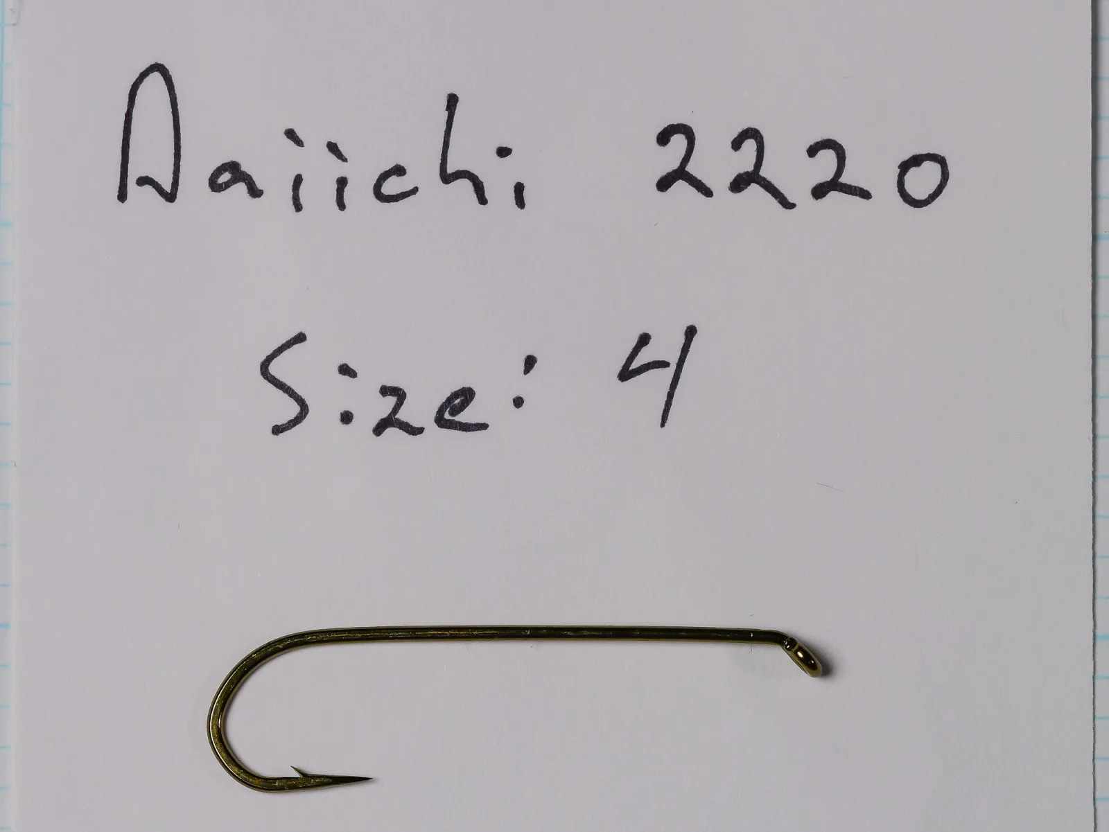 Size 4 hook lying below handwriting on a white card reading 'Daiichi: 2220' and 'Size: 4', with graph paper at the margins.