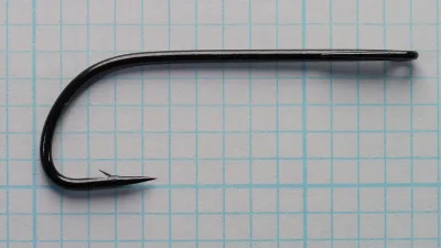 Black hook lying flat on blue grid paper, eye to the right and point to the lower left.