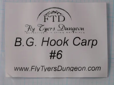 White paper label in a clear plastic packet, printed in black with the FTD logo, the Fly Tyers Dungeon wordmark, B.G. Hook Carp, #6 and the maker's web address.