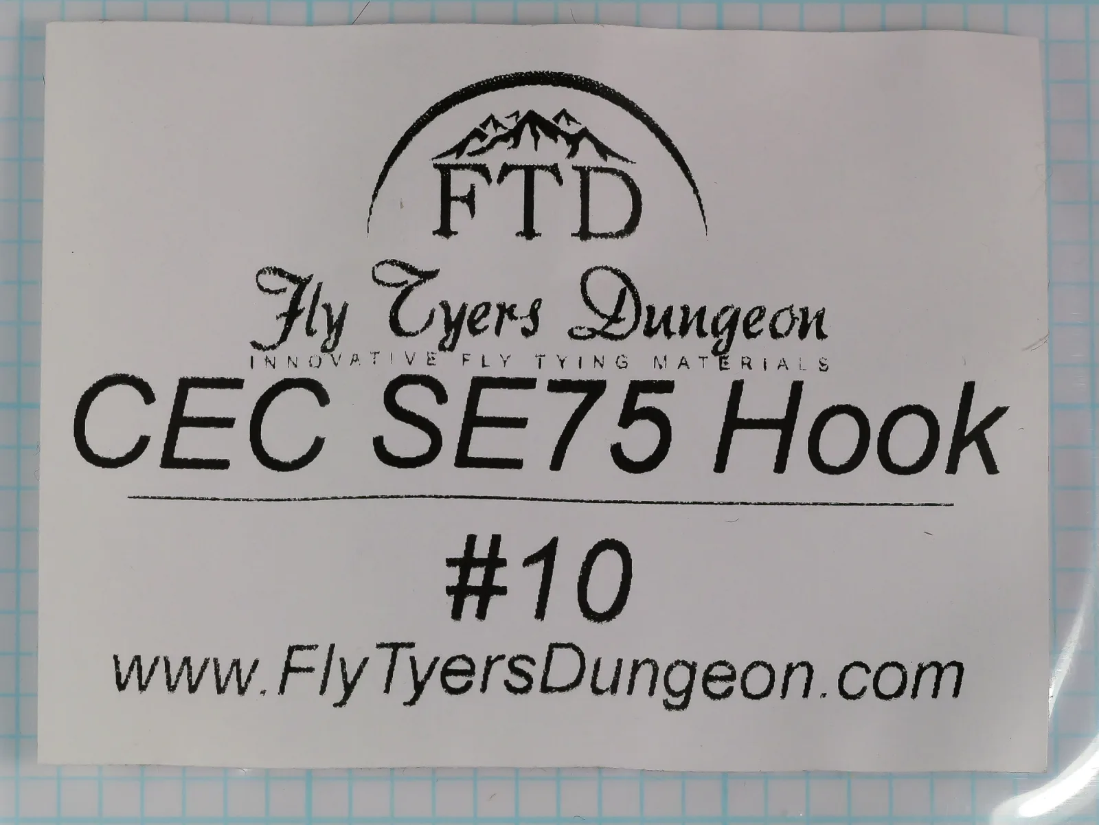 White printed label with an arched mountain-peak logo over FTD, a script Fly Tyers Dungeon wordmark, the line CEC SE75 Hook, the size #10 and the web address www.FlyTyersDungeon.com.