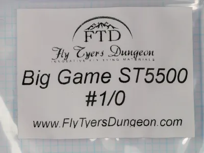 White paper label in a clear plastic bag, printed in black with the FTD logo, the script wordmark Fly Tyers Dungeon, and the lines Big Game ST5500 and #1/0.