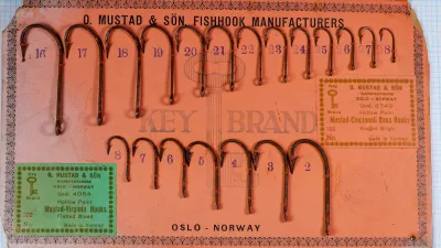Mustad sales card with two rows of rusted hooks: Qual. 3740 hooks above, and seven Qual. 4054 hooks numbered 2 to 8 below, with a green 4054 label at lower left.