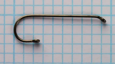 Size 10 Partridge CS2002 hook lying flat on grid paper, with a straight shank, a near-semicircular bend and a small loop at the point end.