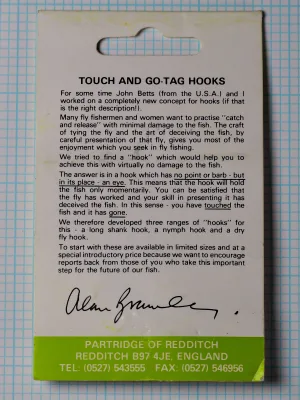 Back of a green Partridge of Redditch card with a printed note headed TOUCH AND GO-TAG HOOKS, a printed signature and a green address band.