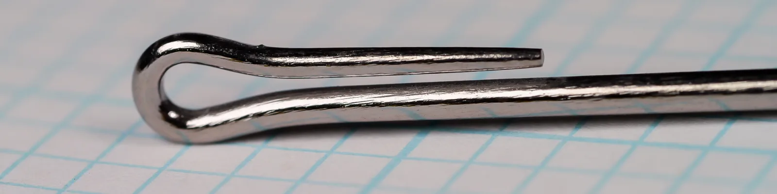 Close side view of the looped eye of a metallic-grey fish hook, the wire bent back into a loop whose tip stops short of the shank.