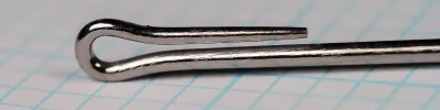 Close side view of the looped eye of a metallic-grey fish hook, the wire bent back into a loop whose tip stops short of the shank.