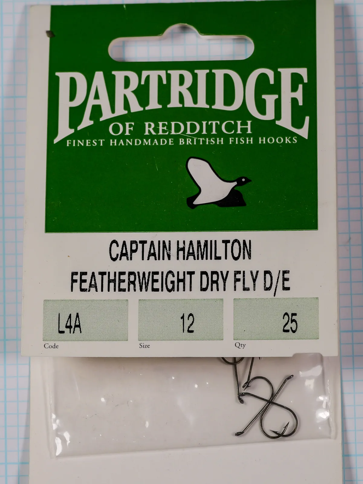 Front of the Partridge L4A green hanger card with the PARTRIDGE wordmark, a bird silhouette, printed code, size and quantity boxes, and a bag of hooks.